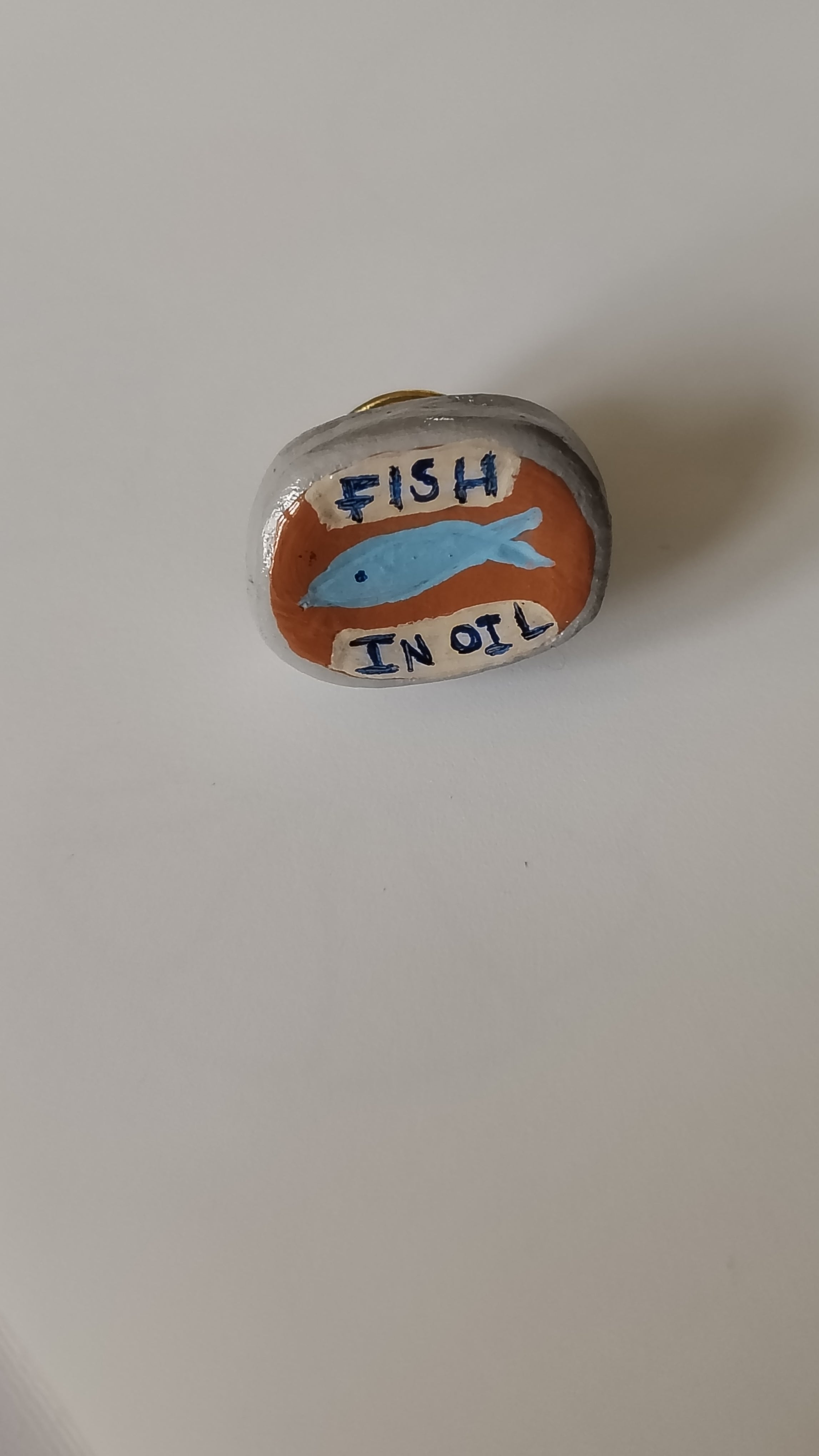 Decorative stone with a fish illustration and text on a plain background